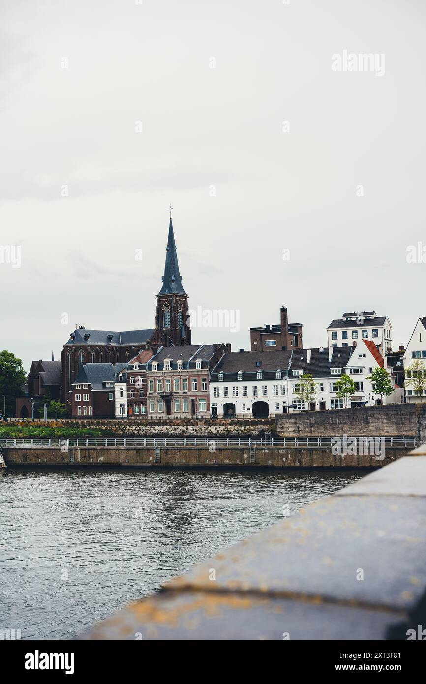 Une scène pittoresque capture l'atmosphère sereine d'Amsterdam, avec des bâtiments traditionnels et une église imposante le long d'une rivière calme, encadrée Banque D'Images
