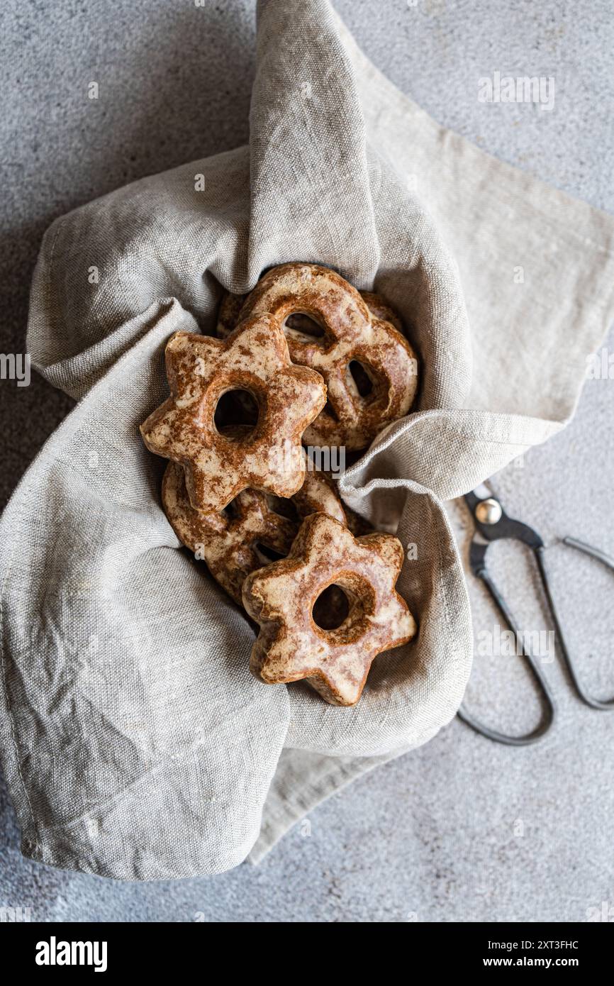 D’en haut, des biscuits en pain d’épices faits maison en forme d’étoiles sont nichés dans un tissu de lin naturel, évoquant une ambiance cosy et rustique. Les biscuits sont poussiéreux Banque D'Images