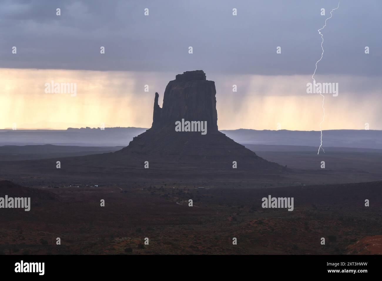 La foudre frappe près d'une butte imposante dans Monument Valley sous des nuages sombres et inquiétants, soulignant la beauté de ce paysage désertique Banque D'Images