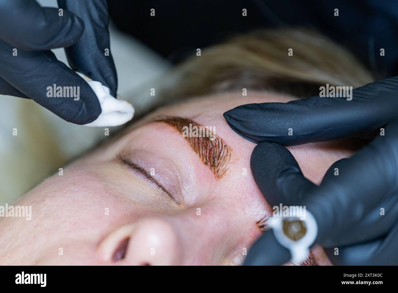 Gros plan d'une esthéticienne utilisant un outil de microblading pour améliorer les sourcils d'un client, mettant en évidence l'application précise et l'attention aux détails dans un p Banque D'Images