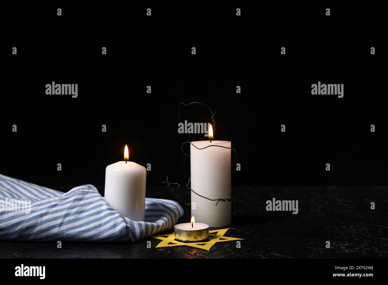 Uniforme de prisonnier, bougies allumées et étoile de David sur fond sombre. Jour du souvenir de l'Holocauste Banque D'Images
