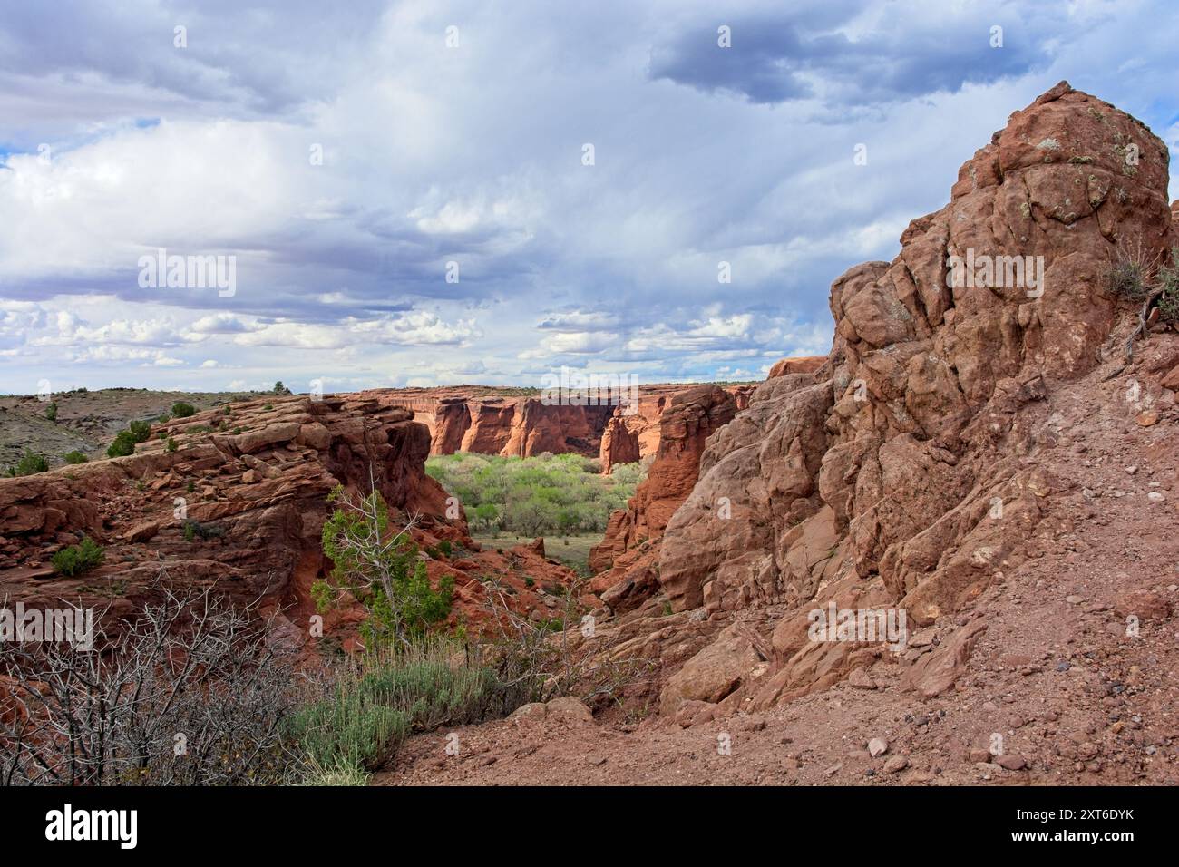 La lumière du soleil illumine les parois du canyon sous un ciel couvert de nuages spectaculaires au Canyon de Chelly National Monument Banque D'Images