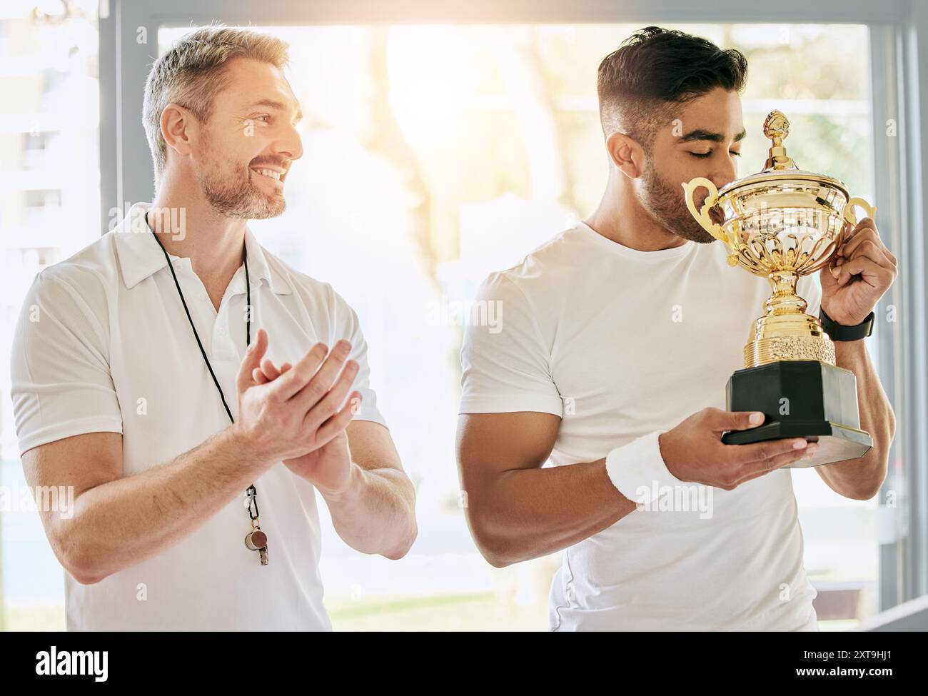 Vainqueur, hommes et baiser avec trophée pour la victoire, la réussite et le succès de la compétition pour l'équipe dans le clubhouse. Récompense, joueur de tennis et entraîneur avec applaudissements Banque D'Images