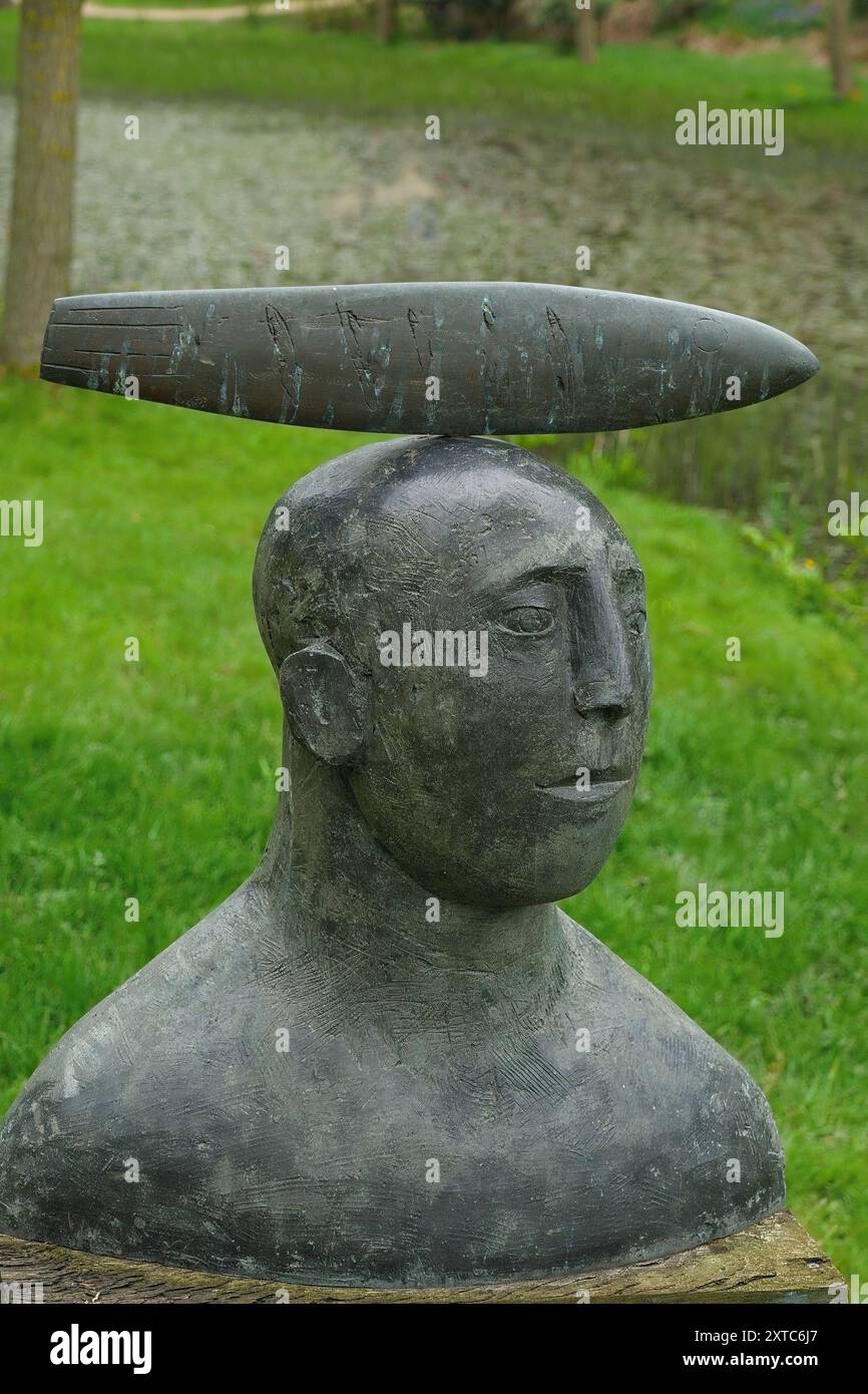 Sculpture abstraite en bronze provoquant la réflexion d'une tête de pêcheur avec une coiffe unique, Himalayan Gardens and sculpture Park, Ripon, Royaume-Uni. Banque D'Images