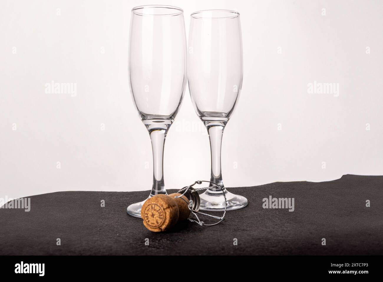 Des verres à champagne vides et un bouchon sur blanc, symbolisant la conclusion d'une fête de Noël ou du nouvel an, avec une touche d'élégance. Banque D'Images