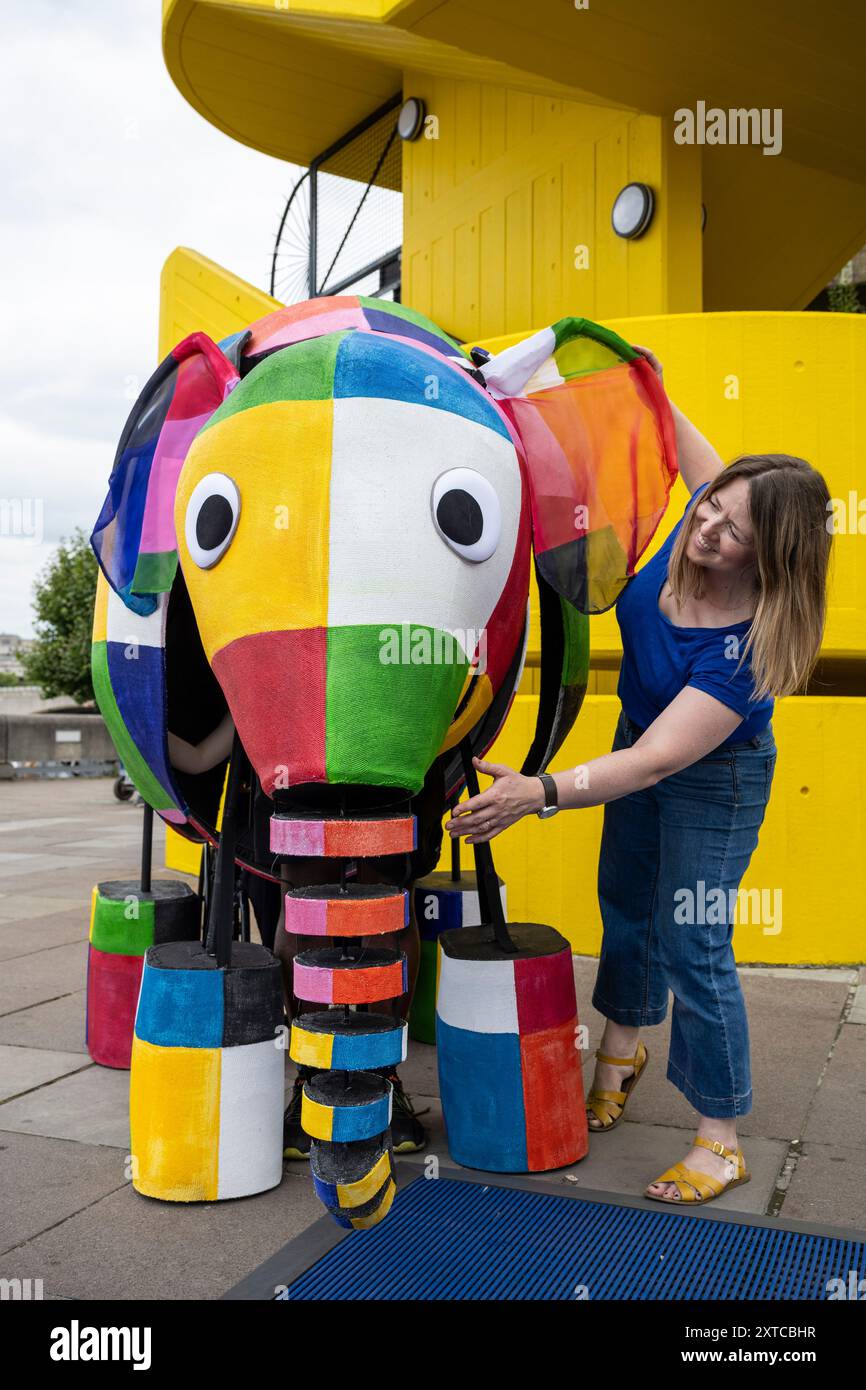 Londres, Royaume-Uni. 14 août 2024. Yvonne Stone, conceptrice et réalisatrice de marionnettes, avec Elmer l’éléphant patchwork, une marionnette géante, faisant sa première apparition publique alors qu’elle défilait devant le Southbank Centre avant de participer à l’adaptation musicale magique de Tall Stories des livres très appréciés d’Elmer de David McKee. Les spectacles auront lieu au Lowry à Salford et au Southbank Centre en octobre. Credit : Stephen Chung / Alamy Live News Banque D'Images