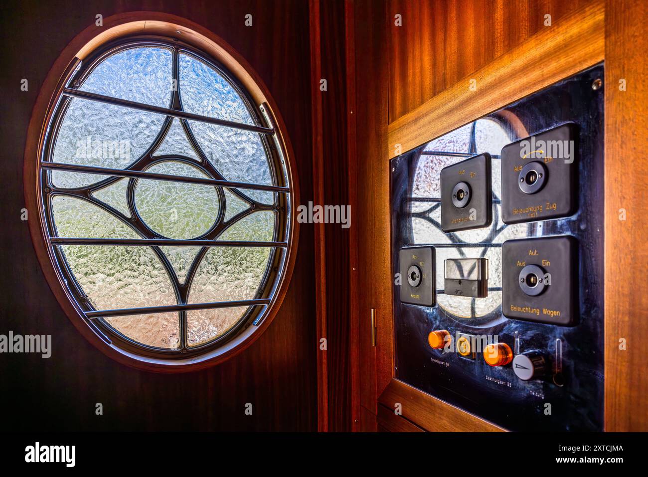 Une fenêtre circulaire en forme de hublot avec un motif floral en verre et un panneau de commande avec des boutons en laiton pour l'éclairage du train et du wagon décorent la porte d'un wagon de l'Alpine Classic Pullman Express. Le train date de 1931 et circulait à l'origine sous le nom de 'Golden Mountain Pullman Express' sur la ligne ferroviaire Montreux–Berner Oberland. Le chemin de fer rhétique l'a acheté en 1939 et l'a utilisé pour des voyages d'inspection de l'armée de 1940 jusqu'à la fin de la guerre. Le Verein Pro Salonwagen, fondé en 1998, a sauvé le train, qui est aujourd'hui un monument ferroviaire historique protégé dans le canton des Grisons. Reichenaue Banque D'Images