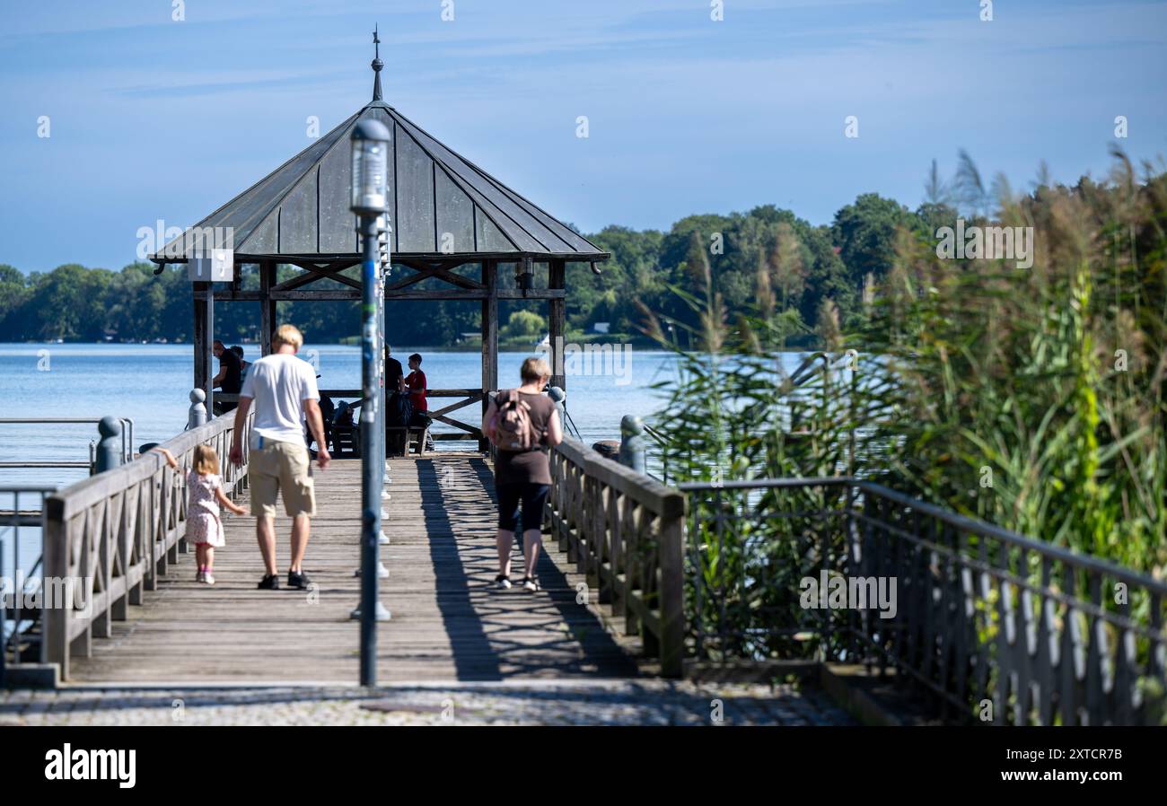 Neuruppin, Allemagne. 12 août 2024. Les gens marchent sur une passerelle sur la promenade au bord du lac Ruppin. Crédit : Monika Skolimowska/dpa/Alamy Live News Banque D'Images
