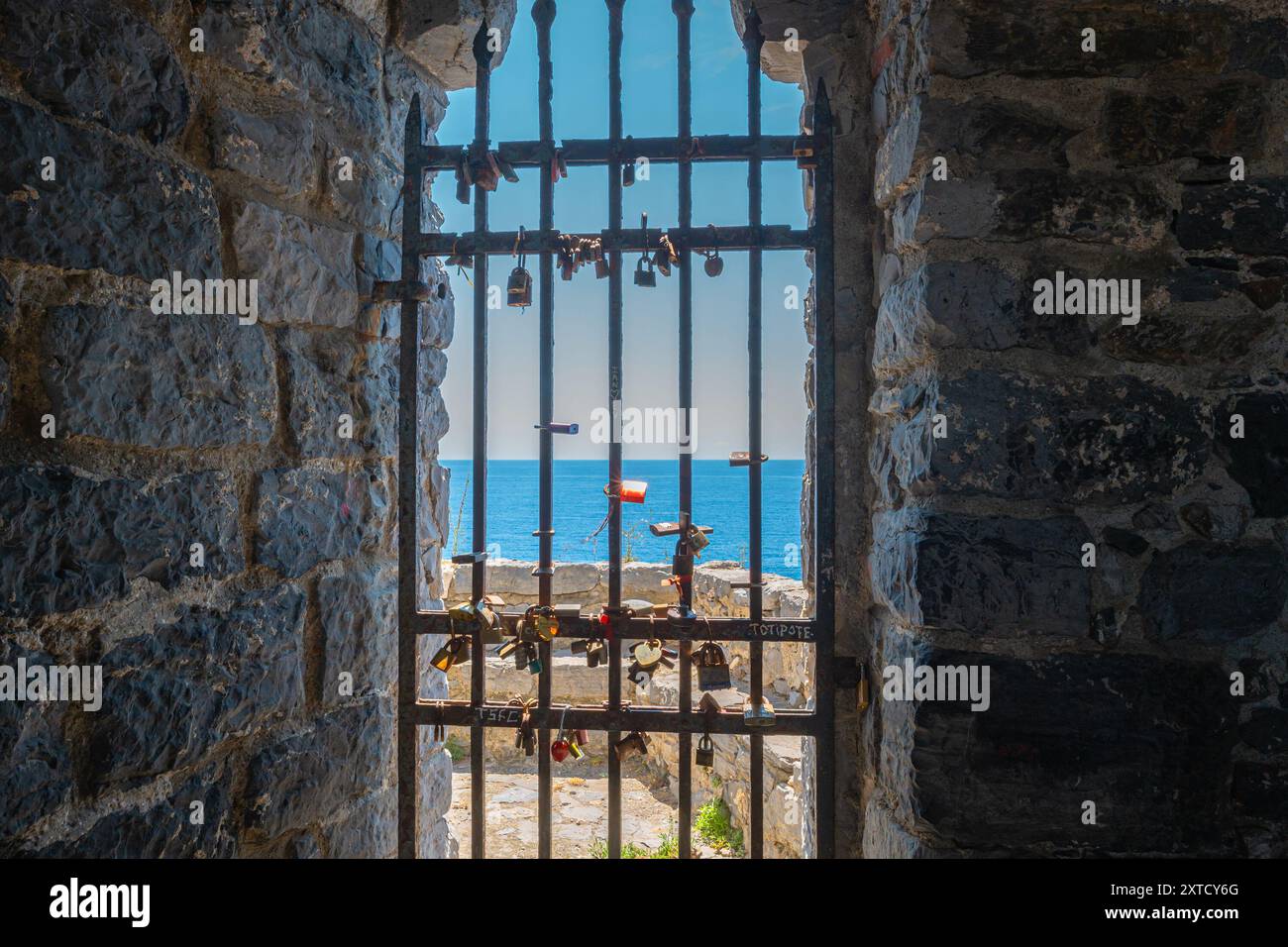 Porte avec clôture en fer et de nombreuses écluses avec la mer Méditerranée en arrière-plan. Église Saint-Pierre (Chiesa di San Pietro) à Porto Venere, Italie Banque D'Images