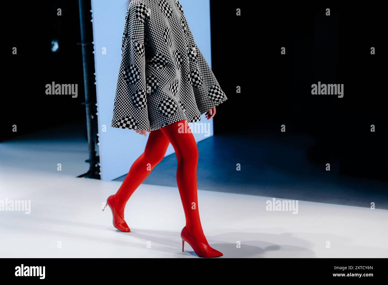 Robe à carreaux noir et blanc sur une figure féminine, collants rouges et chaussures à talons hauts, tenue fantaisie Banque D'Images