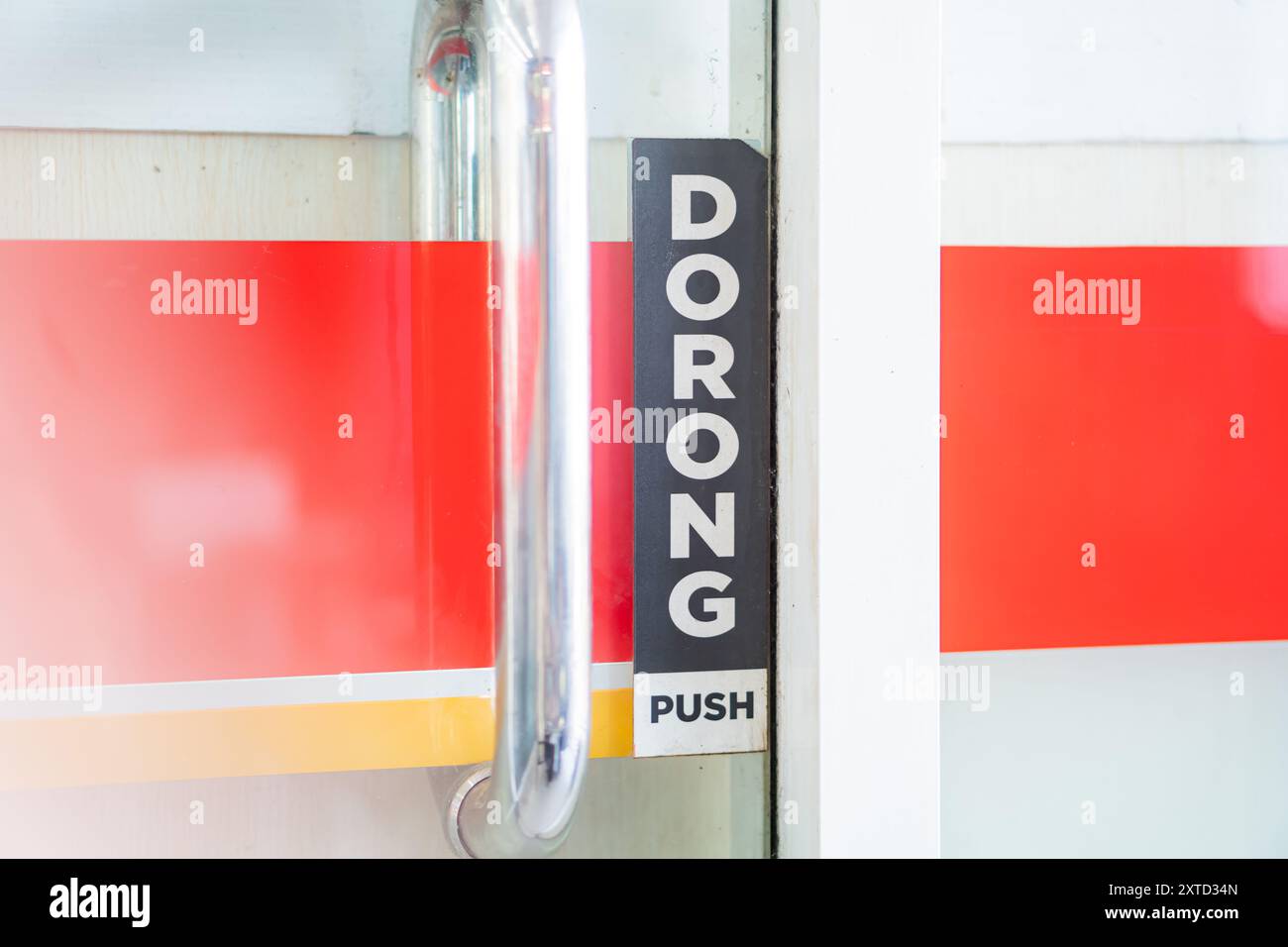 Gros plan d'une poignée de porte avec un panneau indiquant POUSSER indiquant l'action pour ouvrir la porte. La porte présente des bandes rouges et jaunes, créant un vi Banque D'Images