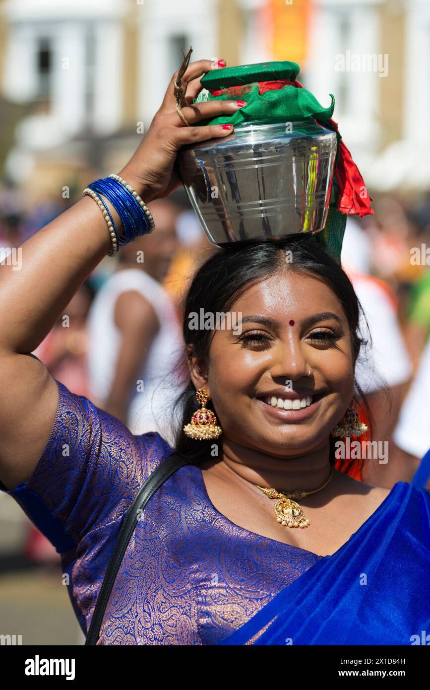 Femme dévote marchant à l'envers portant un pot de lait, connu sous le nom de "paal kudam", sur sa tête pendant le Tamil chariot Festival, un festival hindou. Ealing Banque D'Images