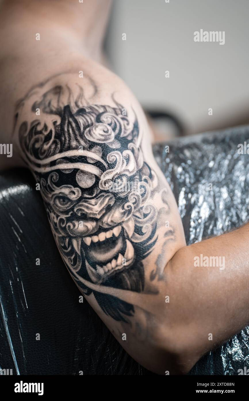 Tatouage noir élégant du masque de démon japonais sur la main de l'homme, art corporel Banque D'Images