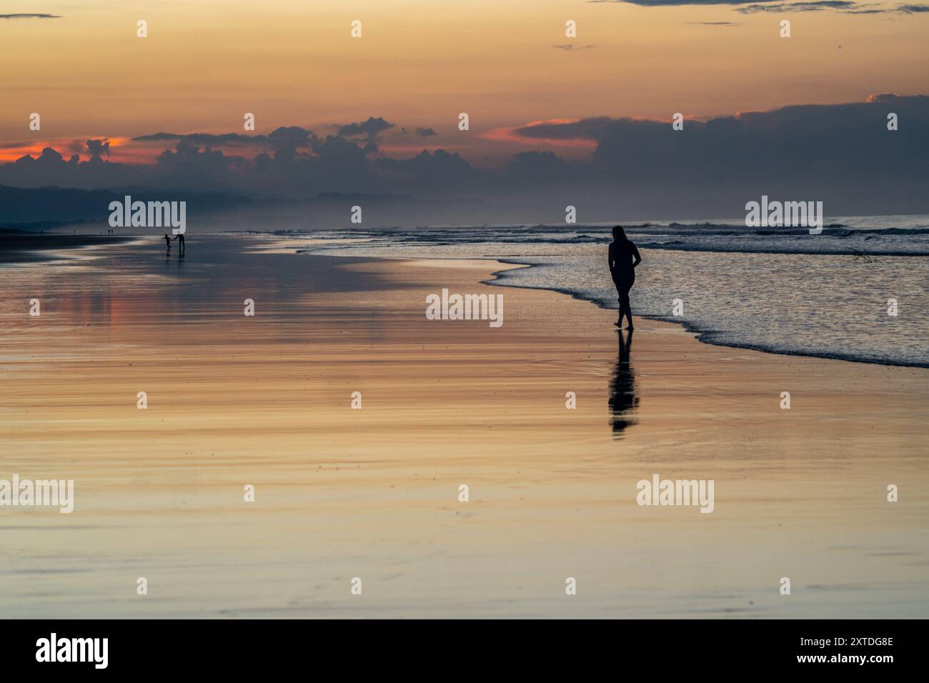 Coucher de soleil sur la plage de Las Lajas, Panama. Les gens marchent sur la plage silhouettée. Banque D'Images