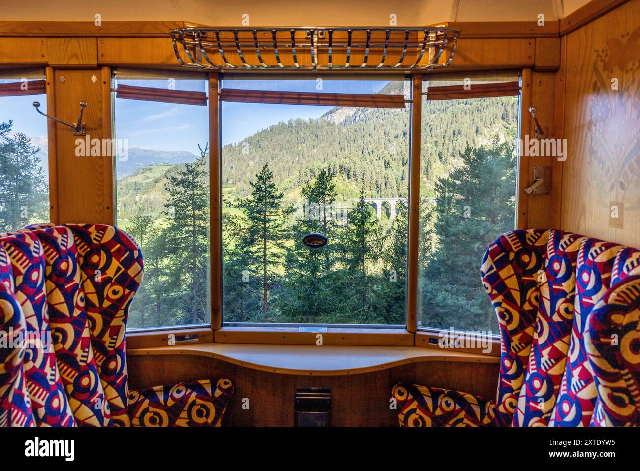 Par la fenêtre de l’Alpine Classic Pullman Express, le viaduc de Landwasser est probablement visible au loin, quelques kilomètres avant de le traverser. Le train date de 1931 et circulait à l’origine sous le nom de « Golden Mountain Pullman Express » sur la ligne ferroviaire Montreux–Berner Oberland. Le chemin de fer rhétique l’a acheté en 1939 et l’a utilisé pour des inspections militaires de 1940 jusqu’à la fin de la guerre. Le Verein Pro Salonwagen, fondé en 1998, a sauvé le train, qui est aujourd’hui un monument ferroviaire historique protégé dans le canton des Grisons. Bahnhofplatz, Bergün Filisur, Grisons, Suisse. Banque D'Images