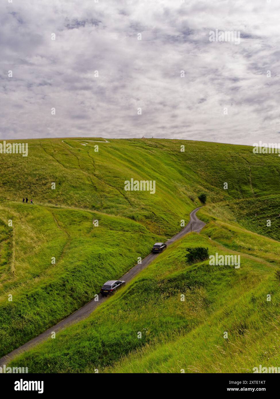 Cheval blanc d'Uffington avec des voitures sur la route et des touristes marchant sur une légère journée couverte à Uffington, Oxfordshire, Angleterre, Royaume-Uni Banque D'Images