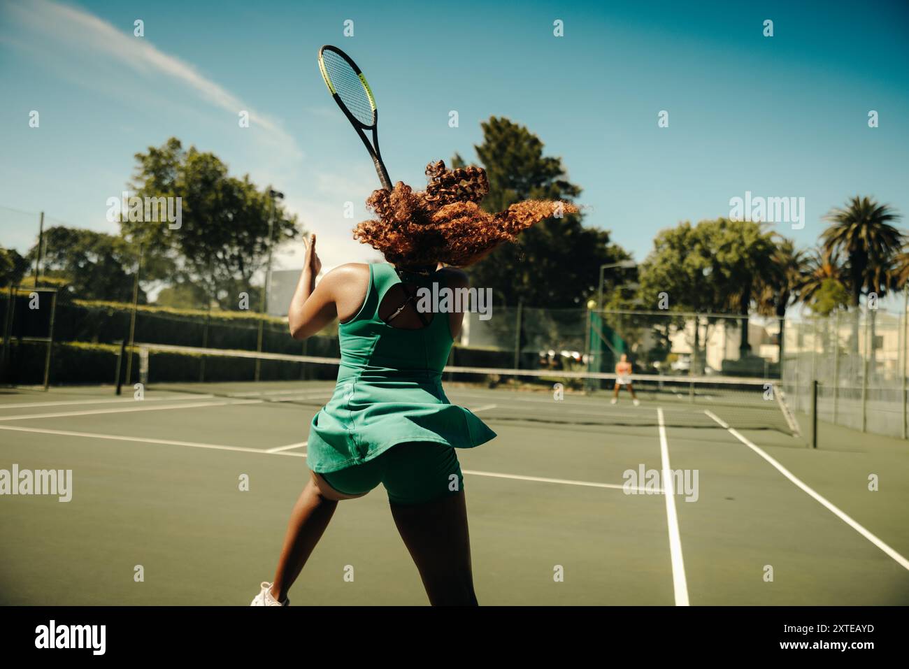 Joueuse de tennis frappant un coup de revers dur lors d'un rallye intense sur un court extérieur, mettant en valeur l'athlétisme puissant et la concentration. Banque D'Images