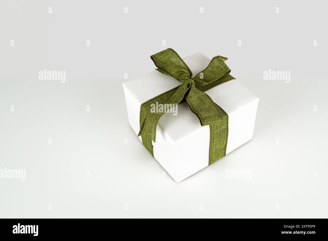 Boîte cadeau blanche attachée avec ruban vert olive sur un fond gris - concept Banque D'Images