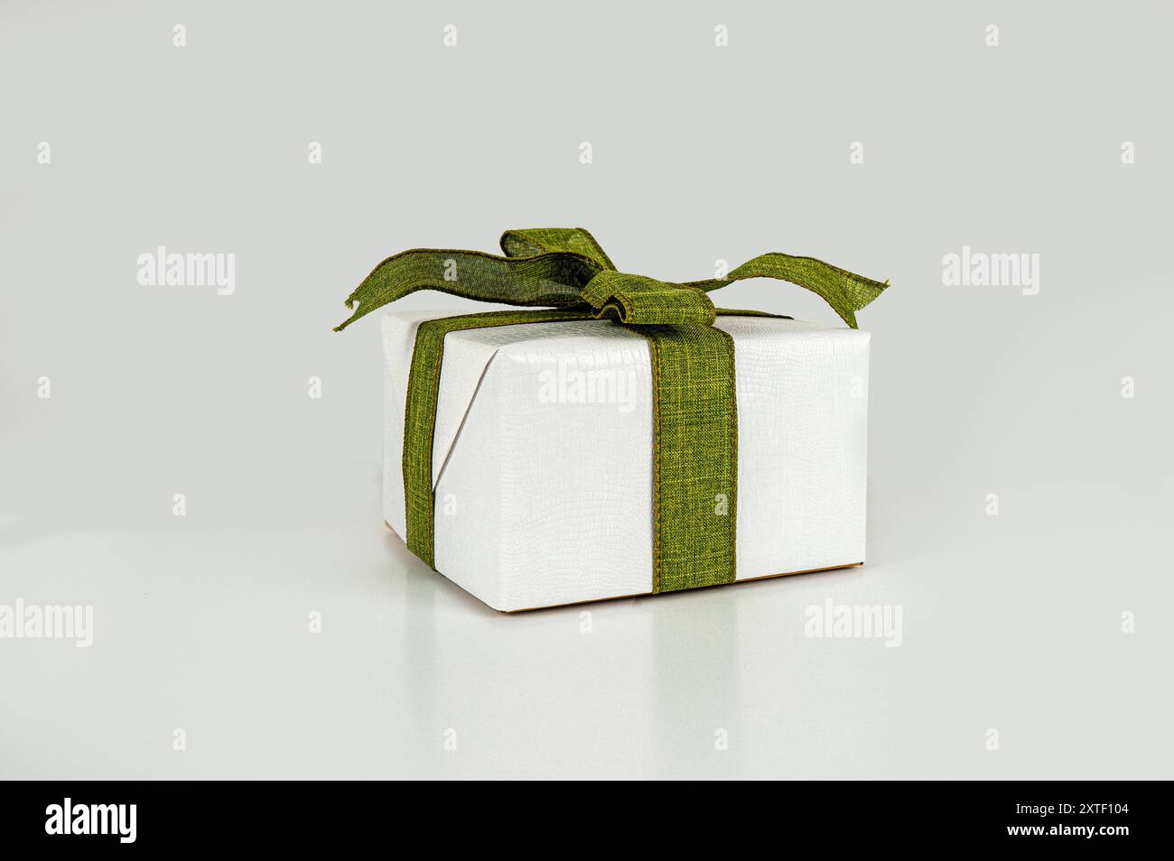 Boîte cadeau blanche attachée avec ruban vert olive sur un fond gris - concept Banque D'Images