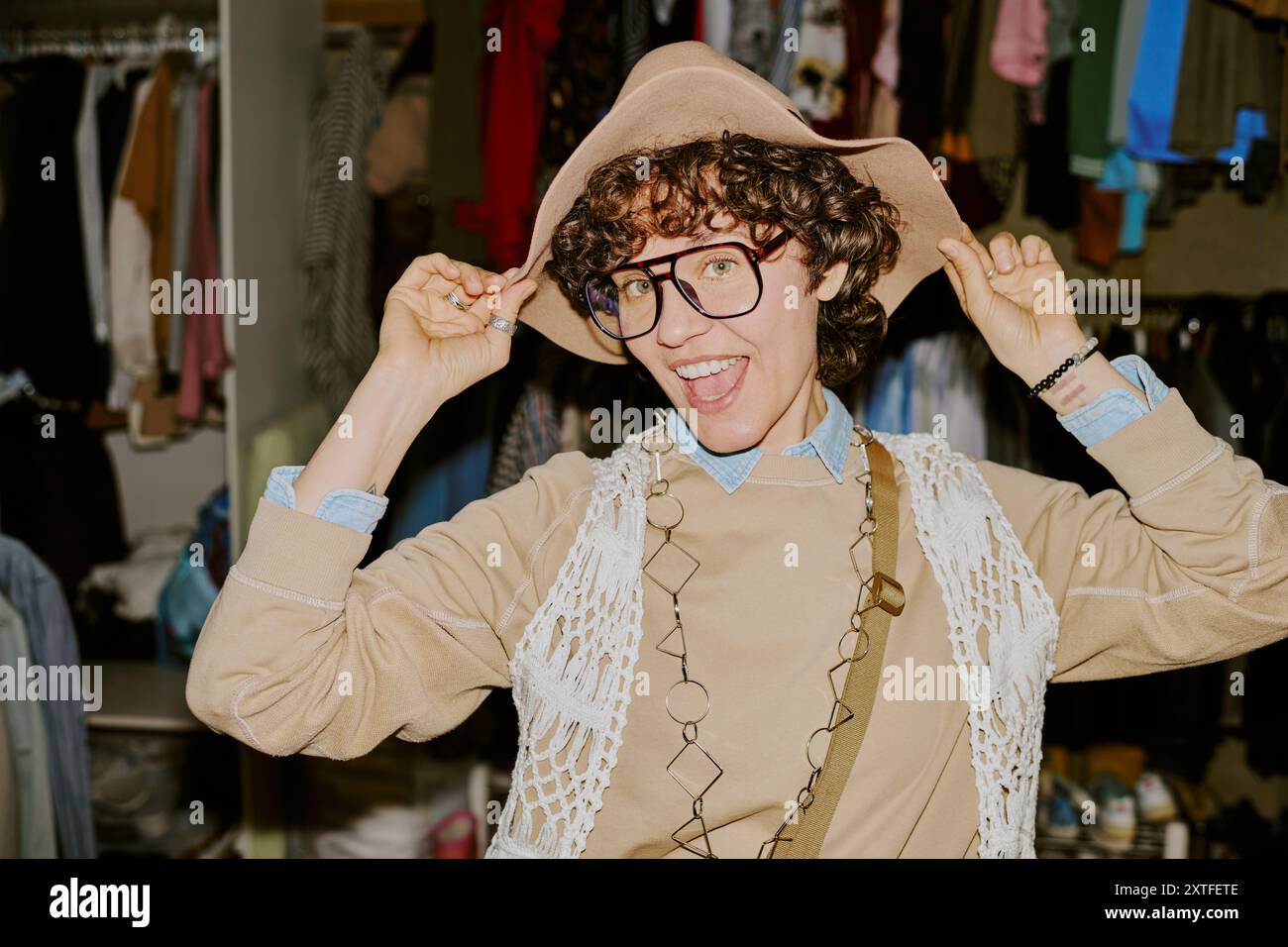 Souriant jeune personne essayant sur chapeau élégant dans le placard Banque D'Images