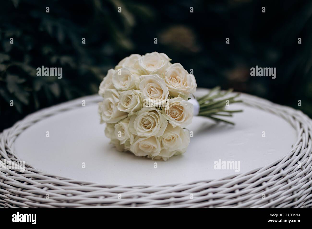 Élégant bouquet de mariage blanc rose sur une table en osier, parfait pour un cadre de cérémonie romantique Banque D'Images