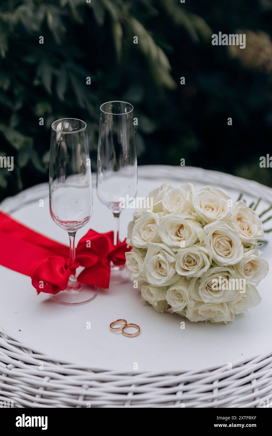 Cadre de mariage élégant avec des roses blanches, des anneaux de mariage et des verres à champagne, parfait pour la célébration Banque D'Images