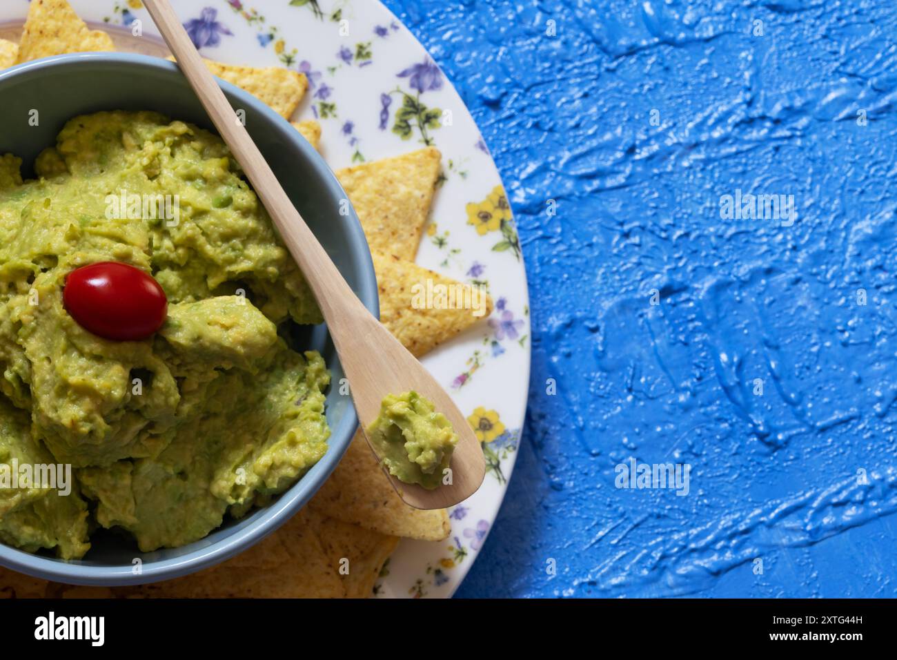 guacamole avec tomates cerises sur le dessus entouré de nachos photographiés de haut en bas. Banque D'Images