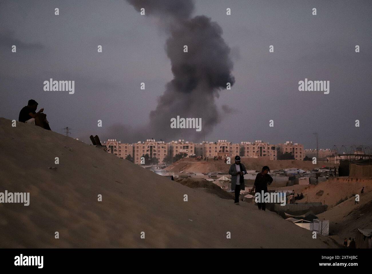 De la fumée s'élève à proximité de la zone des tours Hamad, à l'Ouest de Khan Younis, voyage à Gaza, 14 août 2024. Des avions militaires Iraeli ont attaqué la ville de Hamad alors que l'artillerie explosait des bâtiments résidentiels à Khan Younis, dans le sud de la bande de Gaza, après que des dizaines de personnes eurent été tuées dans des attaques à travers le territoire palestinien au cours des 24 heures précédentes. Les États-Unis et Israël envoient des délégations au Qatar pour des pourparlers de cessez-le-feu qui doivent commencer plus tard aujourd’hui, tandis que le Hamas a déclaré aux médiateurs qu’il était prêt à se réunir après les discussions pour déterminer s’il y avait une réponse sérieuse d’Israël aux propositions de trêve. Photo de Ramez Habboub/ Banque D'Images