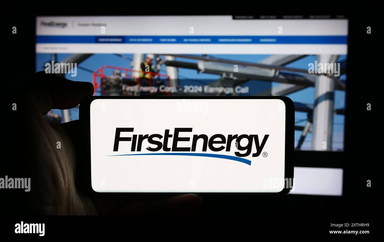 Personne tenant un téléphone portable avec le logo de la société US de services publics d'électricité FirstEnergy Corp. en face de la page Web de l'entreprise. Concentrez-vous sur l'affichage du téléphone. Banque D'Images