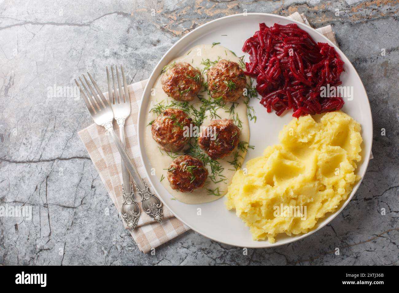 Petites boulettes de viande à la sauce crémeuse servies avec de la purée de pommes de terre et des betteraves en gros plan dans une assiette sur la table. Vue horizontale de dessus Banque D'Images