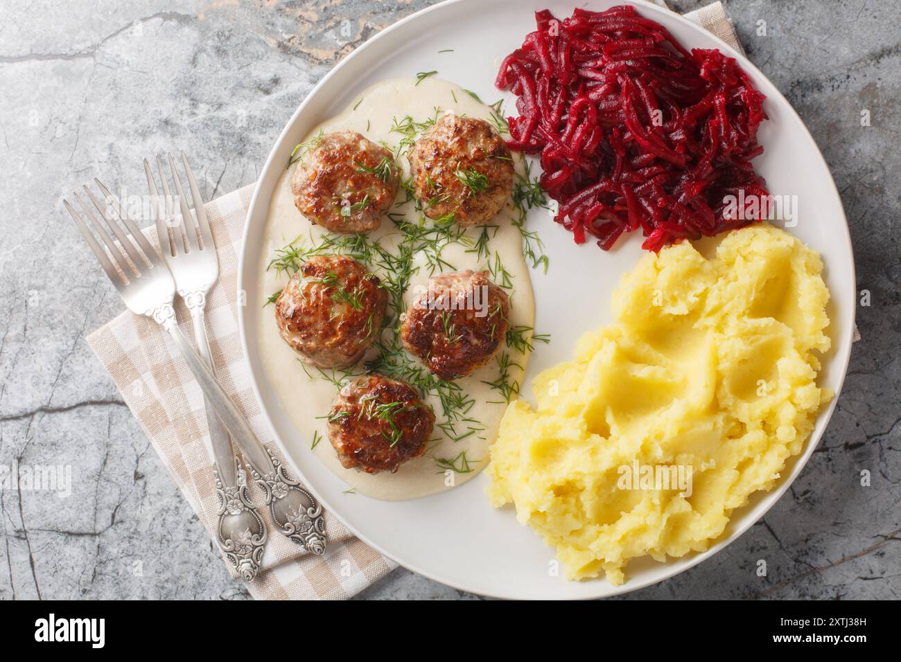 Boulettes de viande traditionnelles à la sauce crémeuse garnies de purée de pommes de terre et de betteraves en gros plan dans une assiette sur la table. Vue horizontale de dessus Banque D'Images