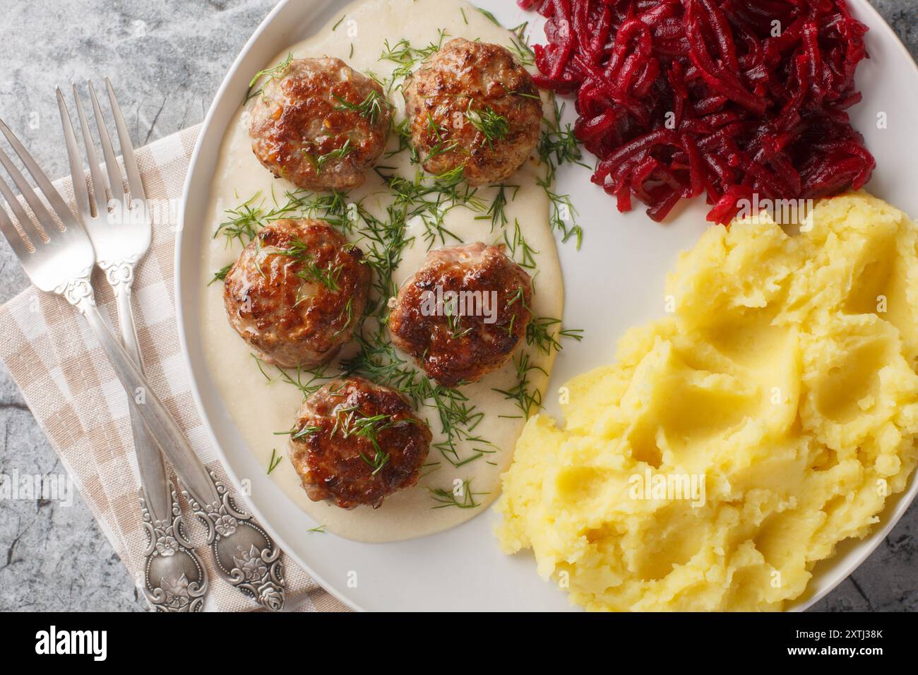 Boulettes de viande tendres servies dans une sauce riche et crémeuse avec de la purée de pommes de terre et une salade de betteraves en gros plan dans une assiette sur la table. Vue horizontale de dessus Banque D'Images