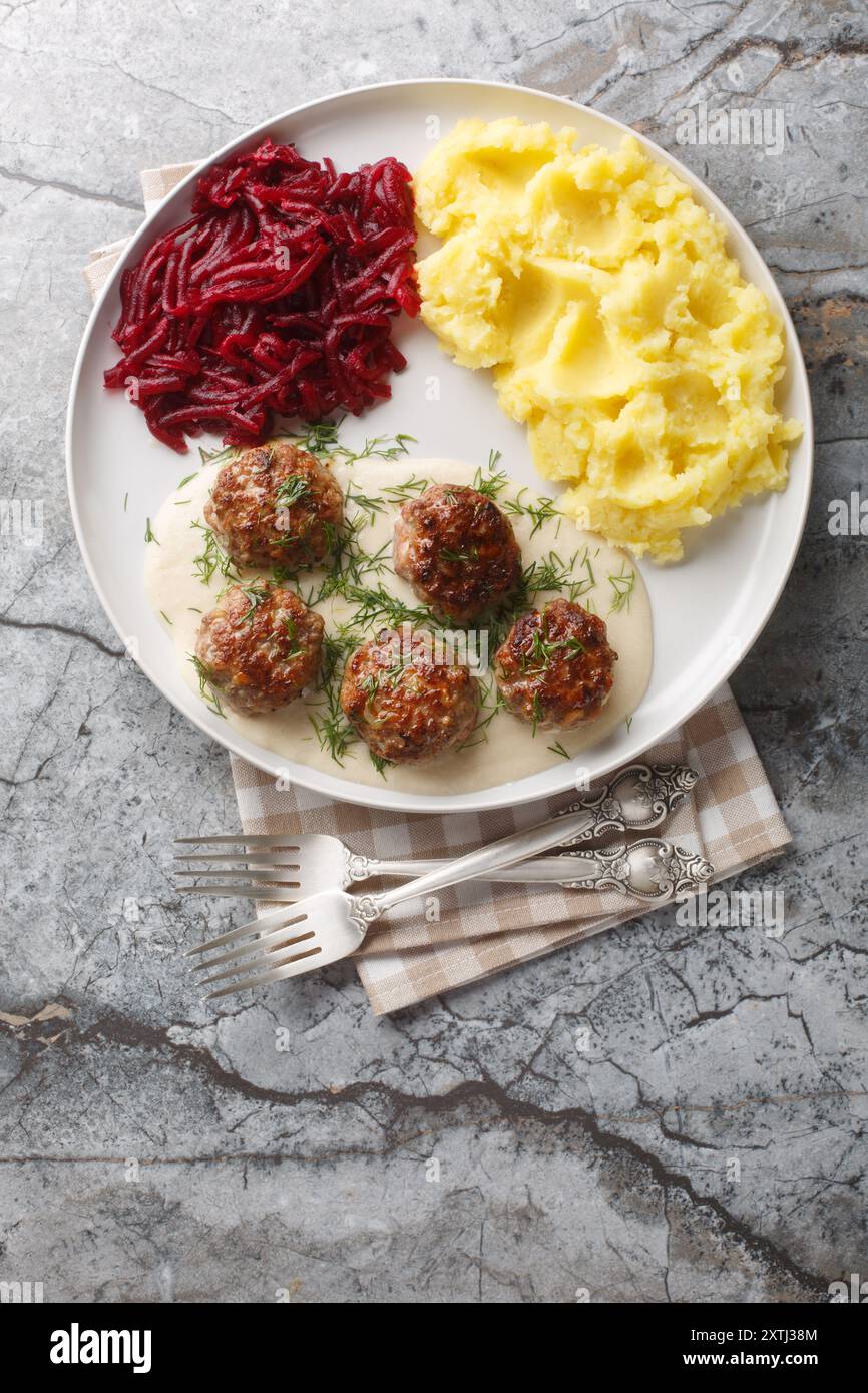 Boulettes de viande polonaises Klopsiki avec purée de pommes de terre et salade de betteraves gros plan dans une assiette sur la table. Vue de dessus verticale Banque D'Images