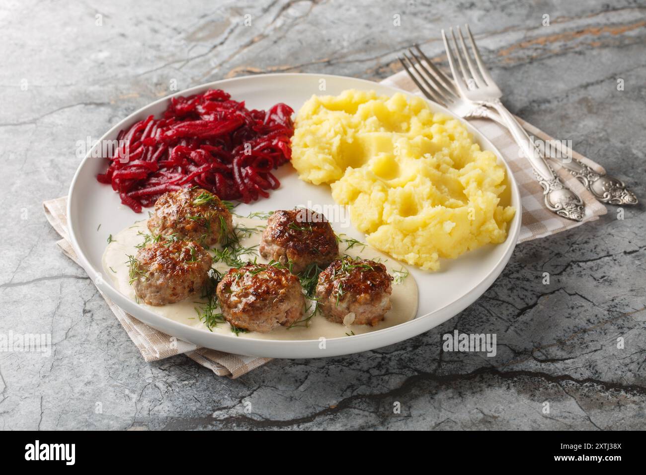 Boulettes de viande traditionnelles à la sauce crémeuse garnies de purée de pommes de terre et de betteraves en gros plan dans une assiette sur la table. Horizontal Banque D'Images
