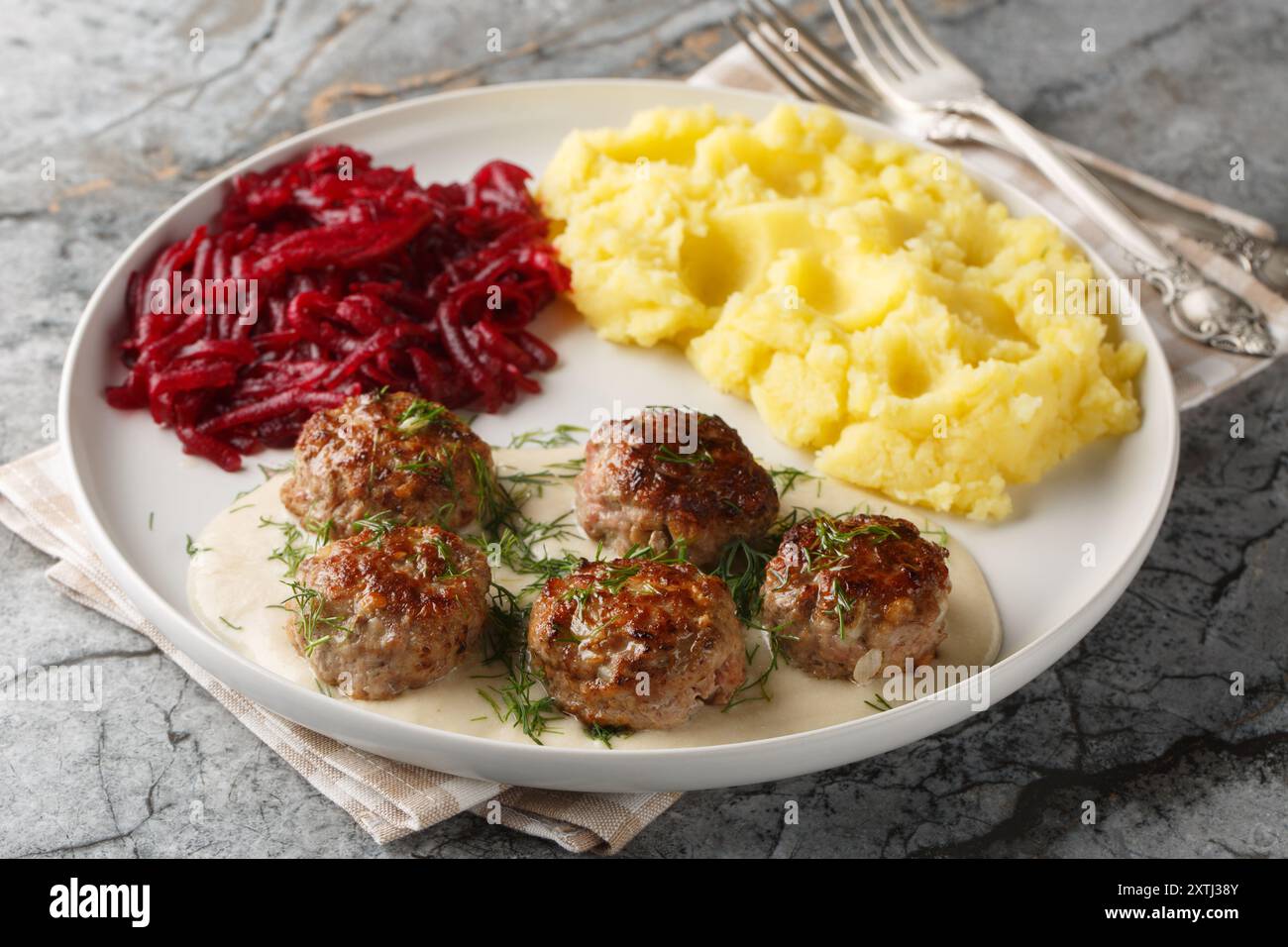 Boulettes de viande tendres servies dans une sauce riche et crémeuse avec de la purée de pommes de terre et une salade de betteraves en gros plan dans une assiette sur la table. Horizontal Banque D'Images