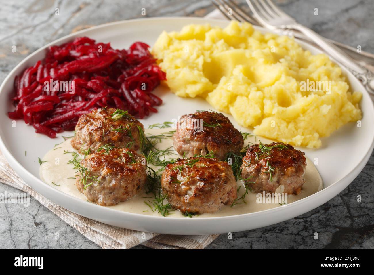 Petites boulettes de viande à la sauce crémeuse servies avec de la purée de pommes de terre et des betteraves en gros plan dans une assiette sur la table. Horizontal Banque D'Images