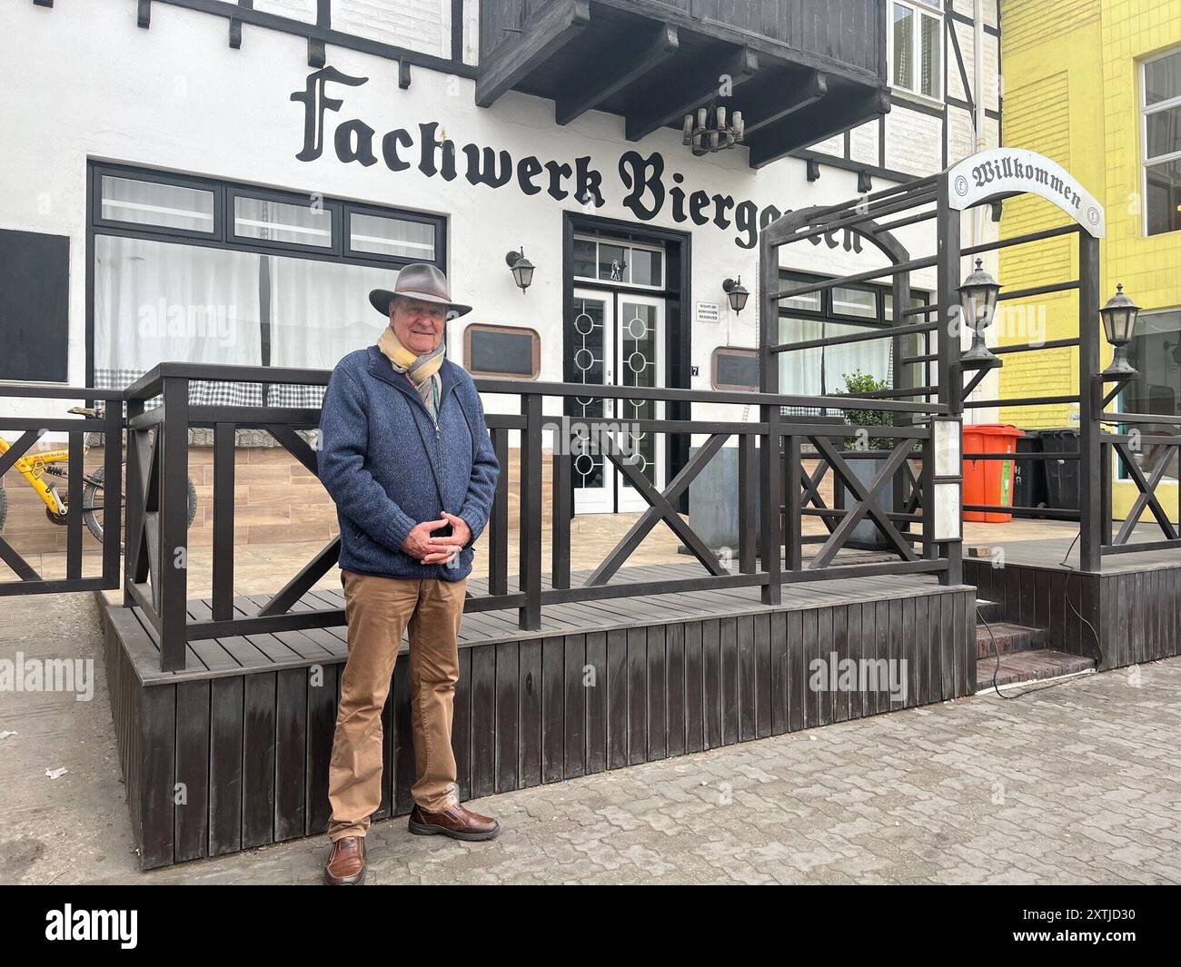 Swakopmund, Namibie. 04 août 2024. Né en Allemagne, le Namibie Raimar von Hase (76) se dresse devant le jardin de bière à colombages dans la ville côtière de Swakopmund. Le bâtiment est l'un des nombreux bâtiments de l'époque impériale. La Namibie est une ancienne colonie allemande (1884-1915), qui était alors appelée Afrique du Sud-Ouest allemande. Crédit : Kristin Palitza/dpa/Alamy Live News Banque D'Images
