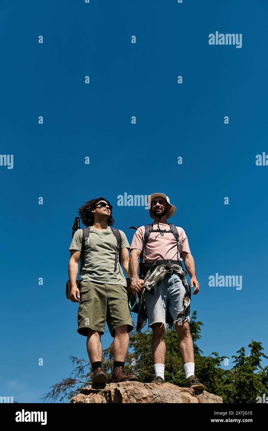 Deux jeunes hommes, un couple gay, partent ensemble en randonnée un jour d'été, profitant de la vue. Banque D'Images