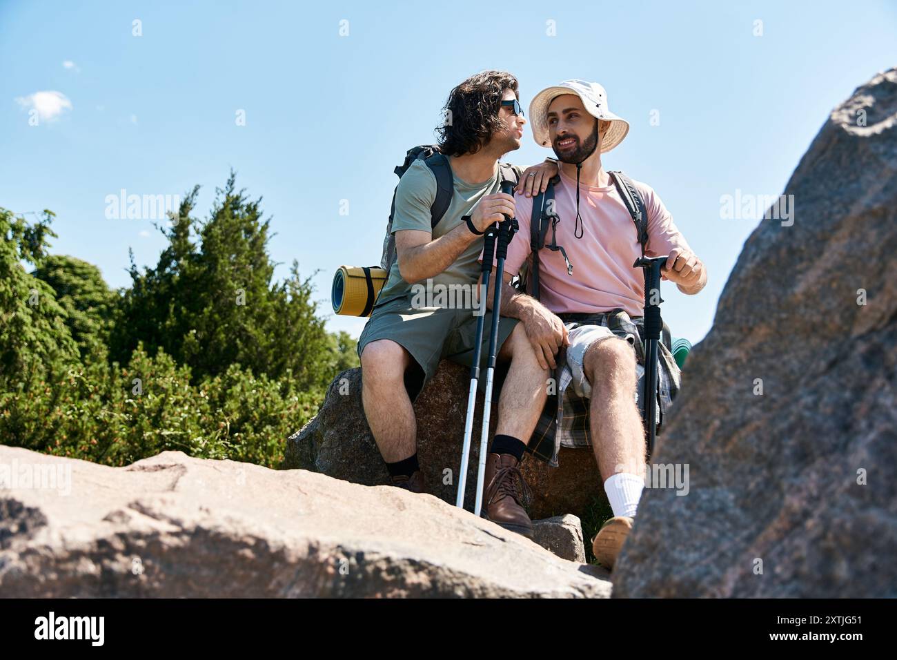 Deux jeunes hommes, un couple gay, font de la randonnée ensemble dans la nature sauvage estivale, profitant de l'air frais et des vues panoramiques. Banque D'Images