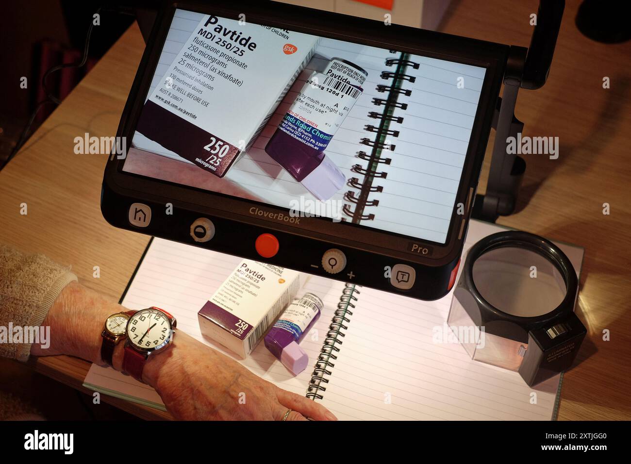 Une dame âgée utilise une aide à la lecture de loupe numérique basse vision pour lire les détails en petits caractères sur son médicament sur un écran d'ordinateur portable UHD Banque D'Images