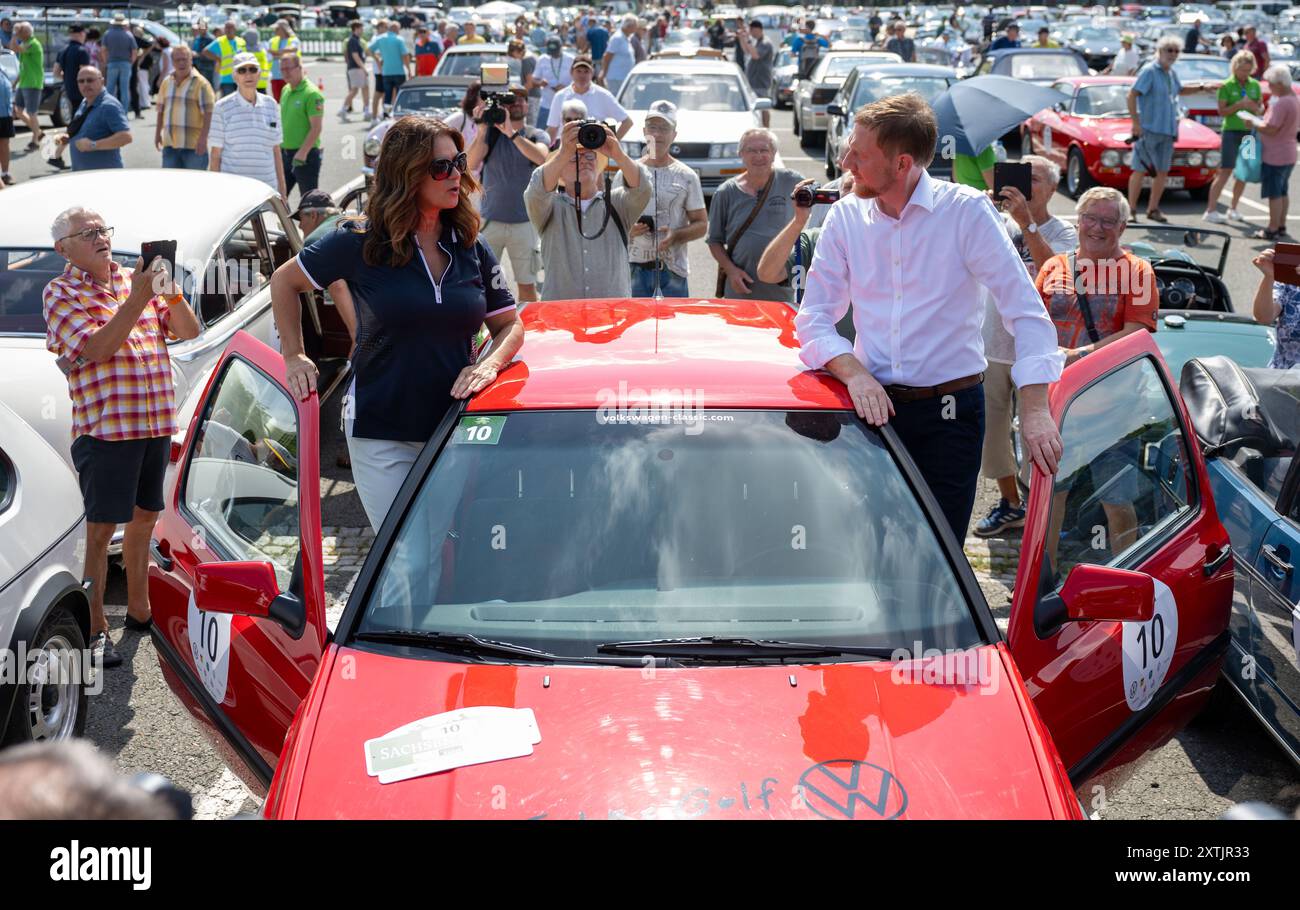 15 août 2024, Saxe, Zwickau : Katarina Witt, championne olympique et championne du monde en patinage artistique, et Michael Kretschmer (CDU), ministre-président de Saxe, discutent avec un modèle anniversaire de VW Golf GTI de 1997 à la Sachsen Classic à Zwickau. Environ 160 équipes prendront la piste dans leurs voitures classiques pour la 21ème édition du rallye de voitures classiques. Le jour du départ, 40 motos historiques seront également sur la route. Le musée du roulis sera sur les routes de Saxe et de Saxe-Anhalt jusqu'au 17 août. Les véhicules devraient ensuite atteindre la ligne d'arrivée à Leipzig. Photo : Hendrik Schmidt/dpa Banque D'Images