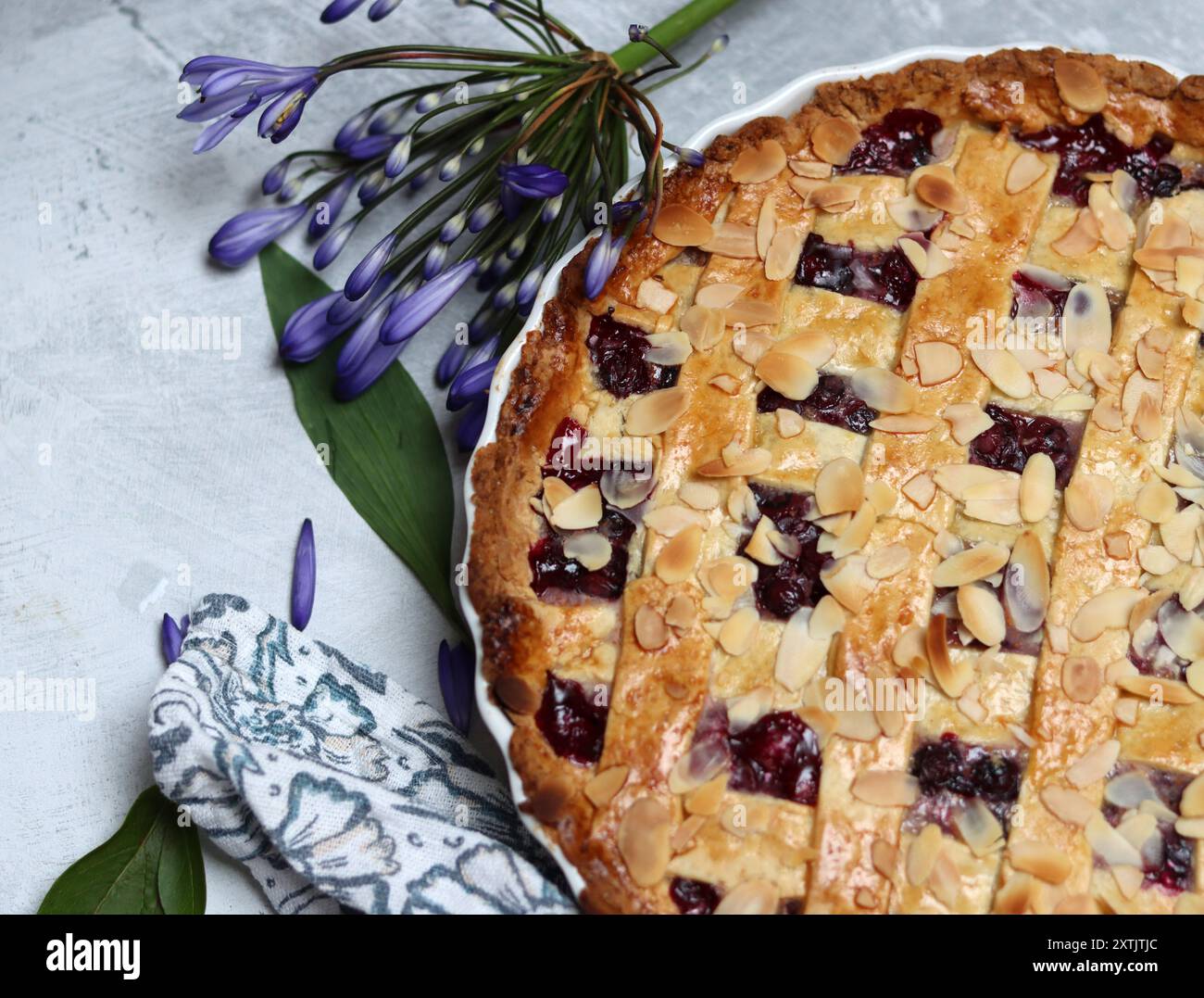 Tarte au treillis de myrtille fraîchement cuite sur une table. Belle croûte dorée en gros plan. Gâteau rond sucré maison. Fond gris clair avec espace de copie Banque D'Images