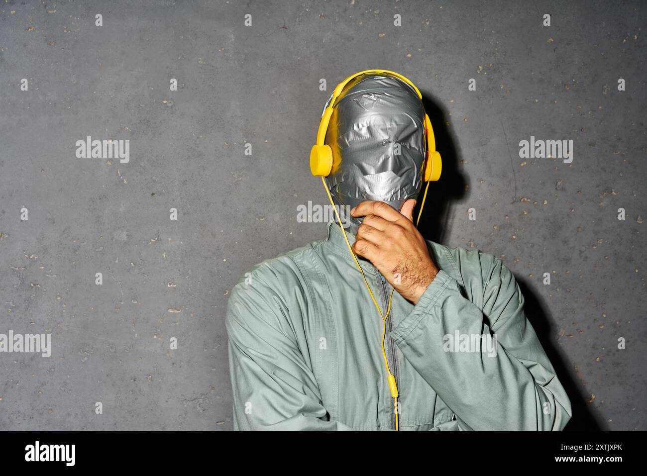 Mystery Man avec bande de conduit visage porter casque écouter de la musique sur fond gris avec espace de copie Banque D'Images