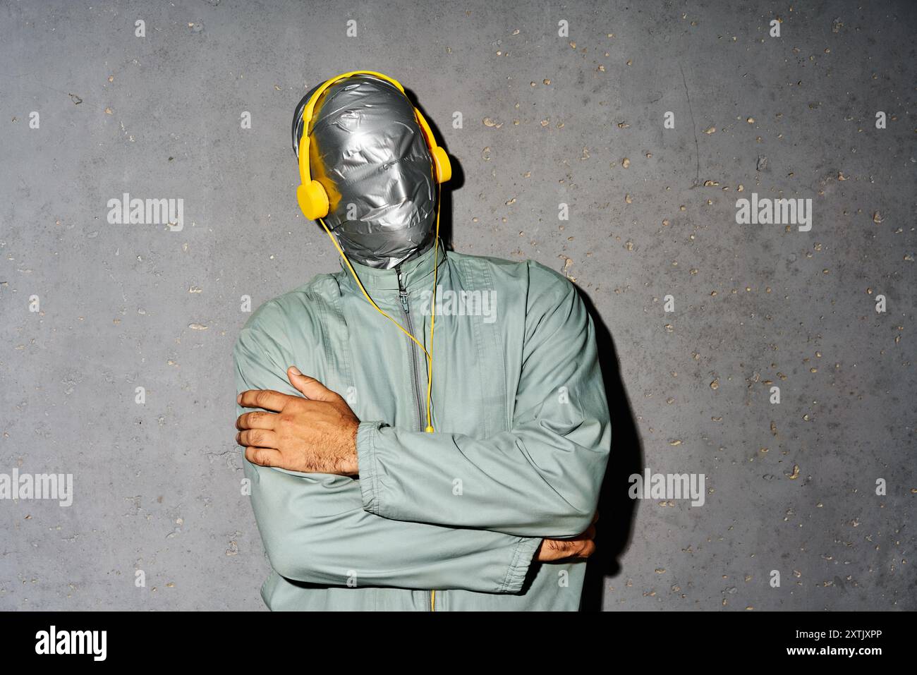 Homme mystère détendu avec bande de conduit visage porter casque écouter de la musique sur fond gris Banque D'Images