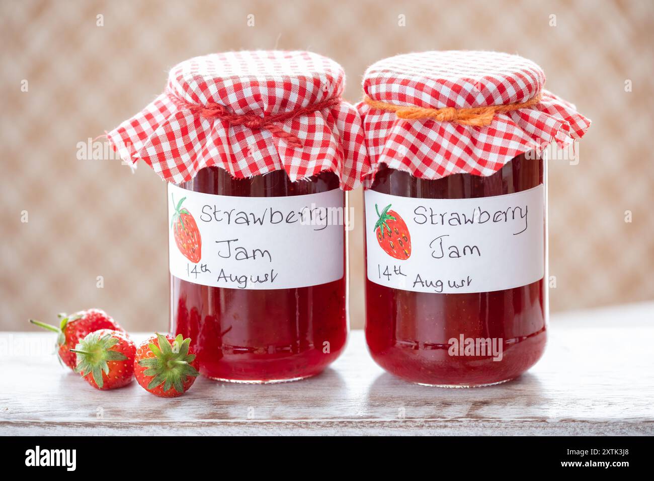 Pots de confiture de fraises maison. Les bocaux en verre ont des étiquettes manuscrites claires et chaque bocal a une garniture en tissu Banque D'Images