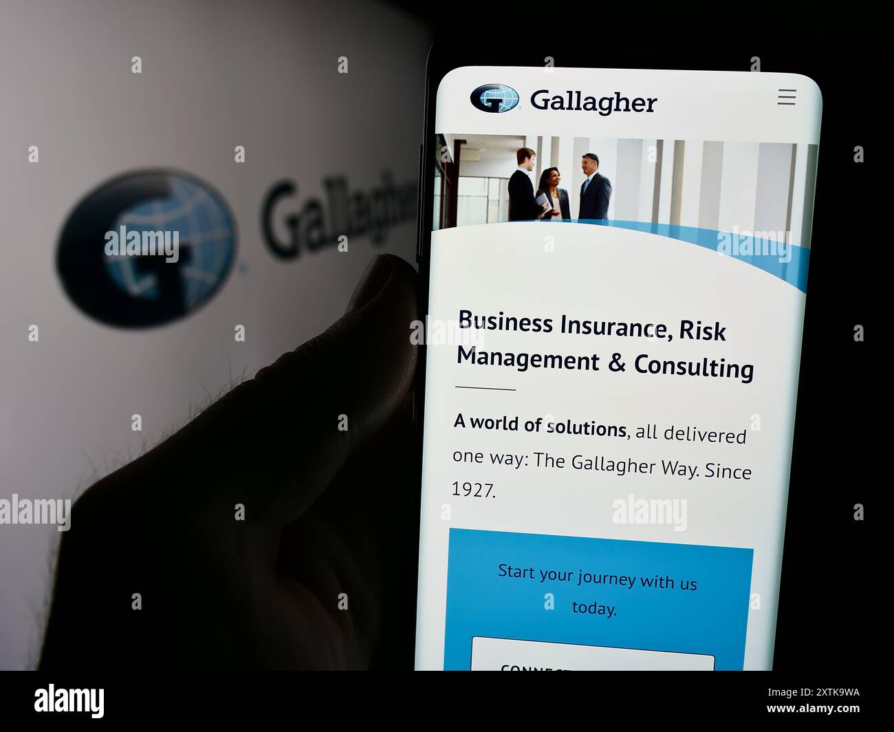 Personne tenant un smartphone avec la page Web de la compagnie d'assurance américaine Arthur J. Gallagher Co. (AJG) devant le logo. Concentrez-vous sur le centre de l'écran du téléphone. Banque D'Images