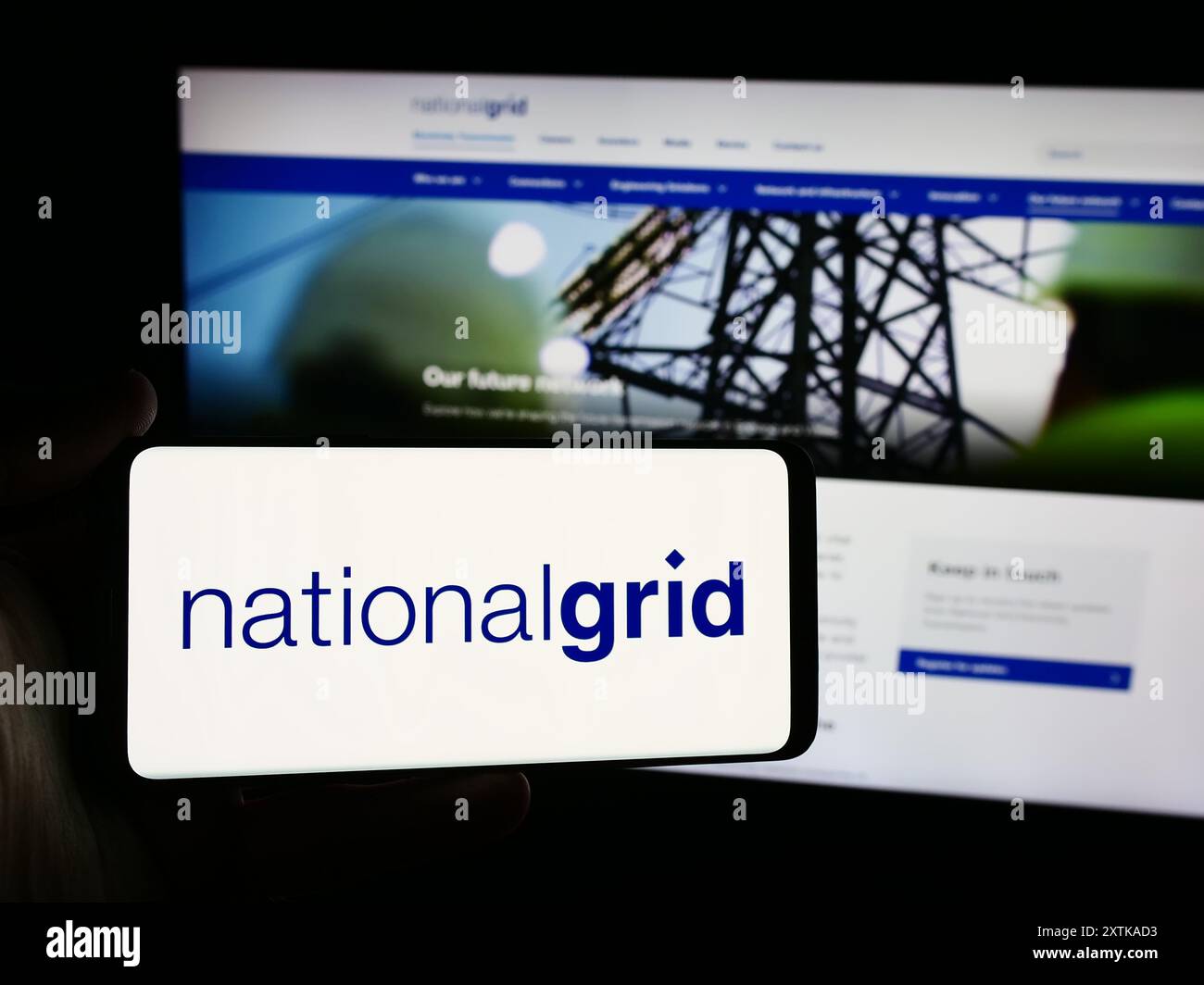 Personne tenant un smartphone avec le logo de la société de services publics britannique National Grid plc en face du site Web. Concentrez-vous sur l'affichage du téléphone. Banque D'Images