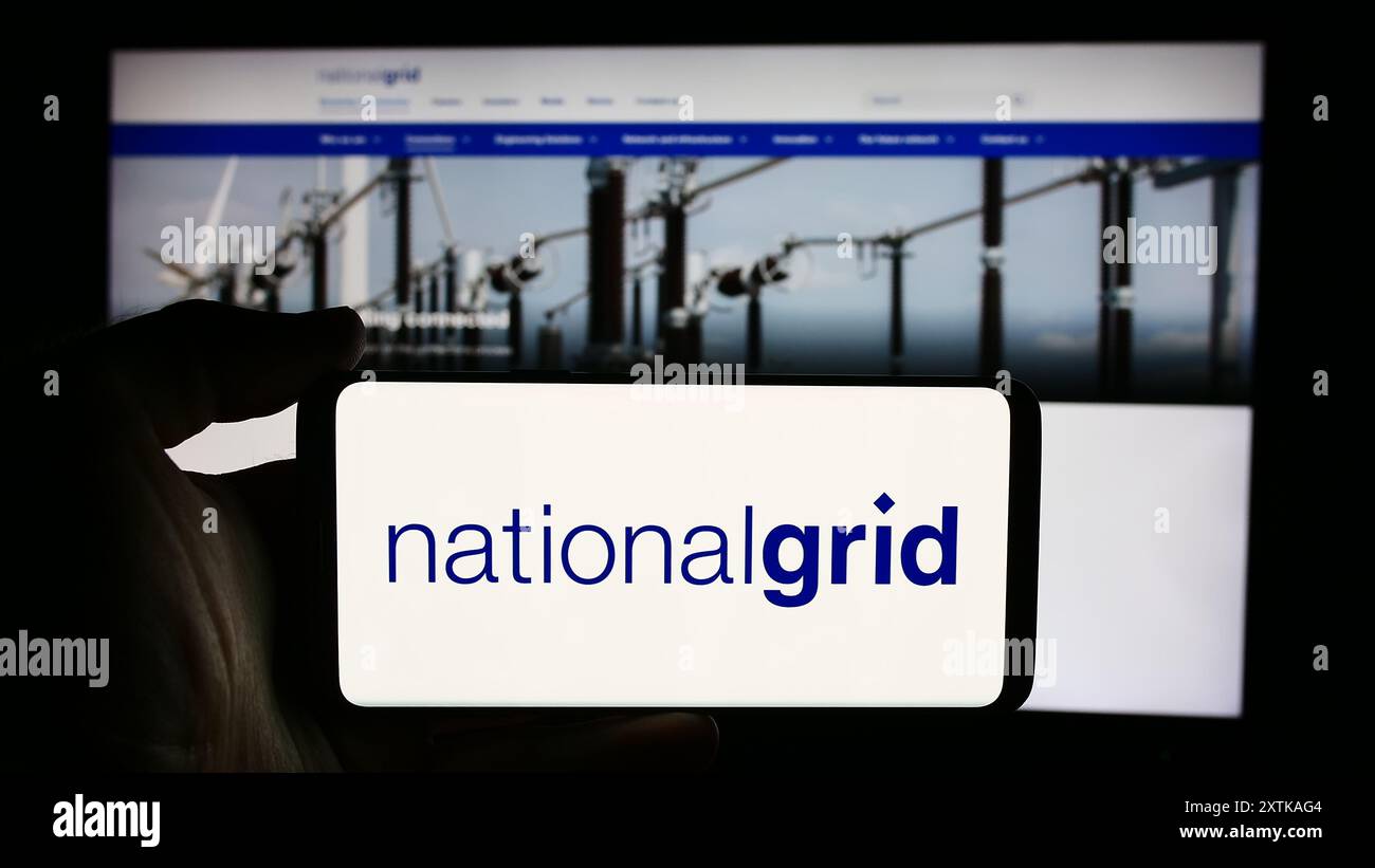 Personne tenant le téléphone portable avec le logo de la compagnie de services publics britannique National Grid plc devant la page Web de l'entreprise. Concentrez-vous sur l'affichage du téléphone. Banque D'Images