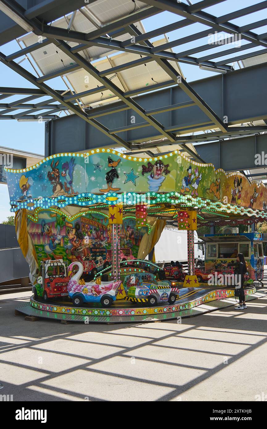 Viladecasn, ESPAGNE - 12 AOÛT 2024 : manège pour enfants à une foire en plein air, mettant en vedette des véhicules colorés et une atmosphère festive, idéal pour la famil Banque D'Images