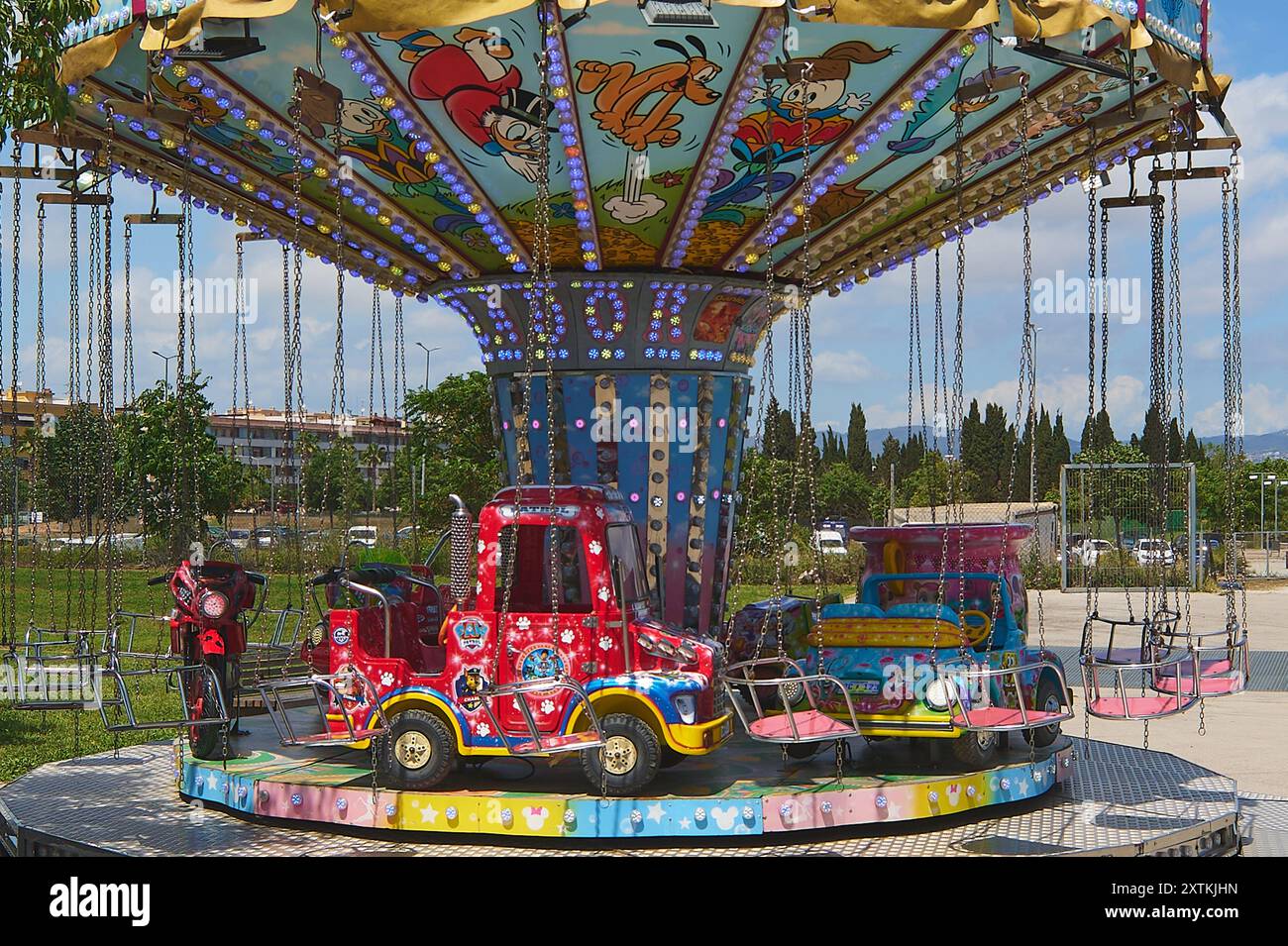 Viladecasn, ESPAGNE - 15 AOÛT 2024 : carrousel pour enfants aux couleurs vives avec des véhicules et des sièges suspendus sous une verrière ornée de dessins animés Banque D'Images